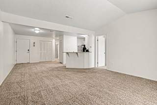 A large, empty living room with a high ceiling and carpeted flooring at Emerald Park Apartments, Kalamazoo, Michigan