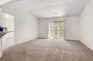 A living room with a carpeted floor and a sliding glass door to a balcony at Emerald Park Apartments, Kalamazoo, Michigan