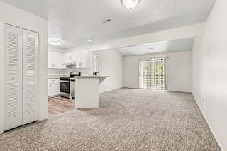 A kitchen with white cabinets and a sliding glass door to a balcony at Emerald Park Apartments, Kalamazoo, Michigan