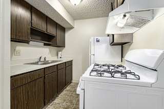Kitchen with brown cabinets and white appliances at Granada Apartments, Jackson, 49202