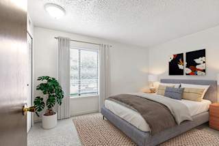 A bedroom with a large window, bed, and a plant at Granada Apartments, Jackson, 49202