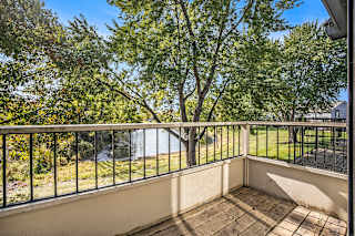 a balcony with a view of a pond and trees at Hampton Lakes Apartments, Michigan, 49534