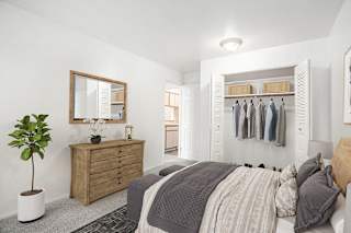 A bedroom with a bed, dresser, and mirror with closet at Hampton Lakes Apartments, Michigan, 49534