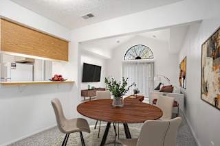 A dining room leading to a living room with a cathedral ceiling at Hampton Lakes Apartments, Michigan, 49534