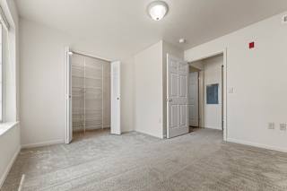A white bedroom with a carpeted floor and a walk-in closet at Hunters Pond Apartment Homes, Illinois, 61820