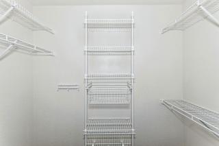 A walk-in closet with wardrobe organizers at Limestone Creek Apartment Homes, Madison