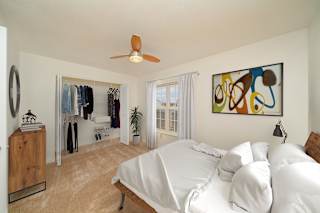 a bedroom with a bed and a ceiling fan and a closet with wardrobe organizers at Limestone Creek Apartment Homes, Alabama