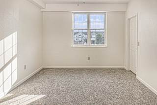 A bedroom with a large window, carpeted floor and a door to a walk-in closet at Limestone Creek Apartment Homes, Madison, AL