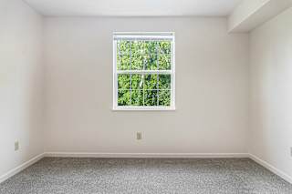 A bedroom with a window and a carpeted floor at Limestone Creek Apartment Homes, Madison, AL