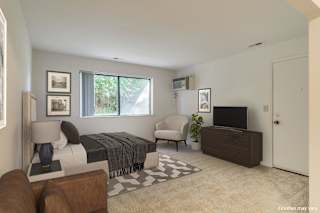 a bedroom with a bed and a dresser in front of a window  at Sycamore Creek Apartments, Michigan