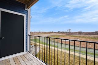 the view from the deck of a home with a gate and a field at Meadowbrooke Apartment Homes, Grand Rapids