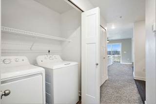 a white laundry room with two washes and a dryer at Meadowbrooke Apartment Homes, Grand Rapids, Michigan