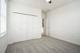 a bedroom with white walls and carpet and a door to a closet at Meadowbrooke Apartment Homes, Grand Rapids, MI