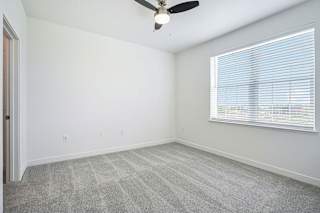 an empty bedroom with a ceiling fan and a window at Meadowbrooke Apartment Homes, Grand Rapids, MI