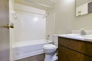 a bathroom with a toilet and a tub and a sink at Old Monterey Apartments, Missouri
