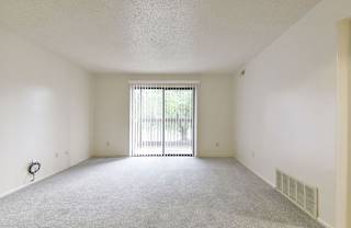 an empty living room with a sliding glass door to a balcony at Old Monterey Apartments, Springfield