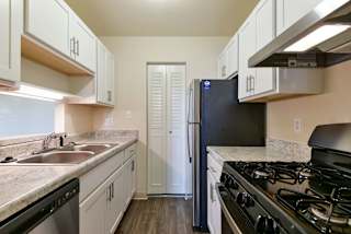a kitchen with stainless steel appliances and white cabinets at Old Monterey Apartments, Springfield