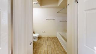 a white bathroom with a toilet and a tub at North Pointe Apartments in Elkhart, IN