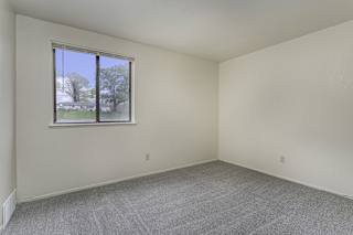 a bedroom with a window and carpeted floor at Normandy Village Apartments, Michigan City, Indiana