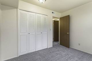 a bedroom with closet doors and a door to a hallway at Normandy Village Apartments, Michigan City