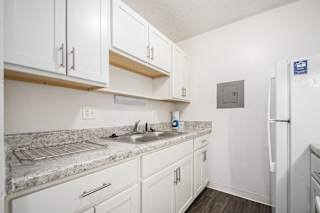 a renovated kitchen with white cabinets and a sink and a refrigerator at Normandy Village Apartments, Indiana