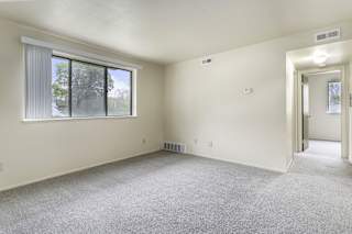 a garden style living room with a large window and carpeting at Normandy Village Apartments, Michigan City, IN