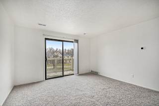 an empty living room with a sliding glass door to a balcony at Normandy Village Apartments, Michigan City, IN, 46360