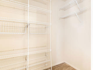 a white walk-in closet with wardrobe organizers in a bedroom  at Oak Shores Apartments, Oak Creek, 53154