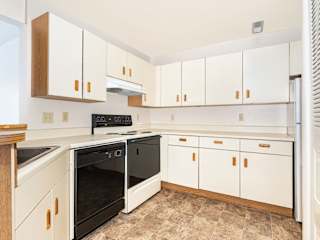 a kitchen with white cabinets and a black stove and oven  at Oak Shores Apartments, Wisconsin, 53154