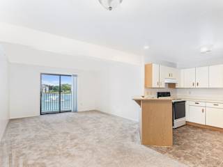an empty living room and kitchen with a door to a balcony  at Oak Shores Apartments, Oak Creek, Wisconsin