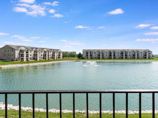 a pond with a fountain in front of an apartment building  at Oak Shores Apartments, Oak Creek, WI, 53154
