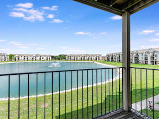 a balcony with a view of a lake and some apartment buildings  at Oak Shores Apartments, Oak Creek, WI