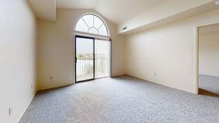 an empty living room with a glass door to a balcony  at Oak Shores Apartments, Oak Creek