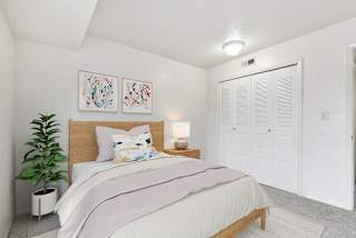 A bedroom with a bed, two pictures on the wall, a potted plant, and a closet door at Old Monterey Apartments, Missouri