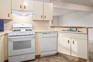 A kitchen with a white stove and oven at Pine Knoll Apartments, Battle Creek, MI