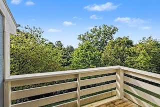 A wooden balcony overlooks a lush green area at Pine Knoll Apartments, Battle Creek