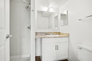 A white bathroom with a shower, sink, and toilet at Pine Knoll Apartments, Battle Creek