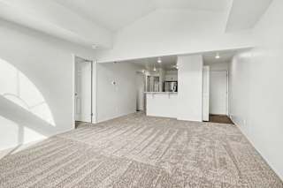 A large, empty dining room with a carpeted floor and white walls at Pine Knoll Apartments, Battle Creek