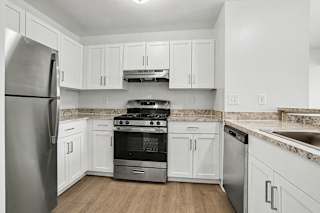 A kitchen with white cabinets and a stainless steel refrigerator at Pine Knoll Apartments, Battle Creek