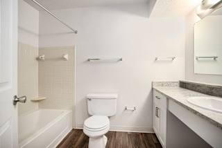 A white bathroom with a toilet, sink, and bathtub at Pine Knoll Apartments, Battle Creek, 49014