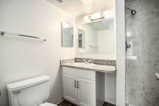A bathroom with a shower, sink with vanity and a toilet at Pine Knoll Apartments, Battle Creek, 49014