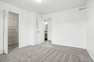 A bedroom with a carpeted floor and a walk-in closet at Pine Knoll Apartments, Battle Creek