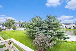 the view of a pond from a balcony with trees at Pine Knoll Apartments, Battle Creek, 49014