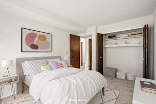 a bedroom with white walls and a white bed with colorful pillows at Sycamore Creek Apartments, Michigan