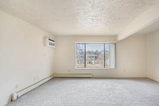 A spacious living room with a window and a carpeted floor at Seville Apartments, Michigan