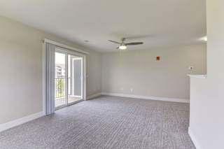 an empty living room with a ceiling fan and a door to a balcony  at Signature Pointe Apartment Homes, Alabama