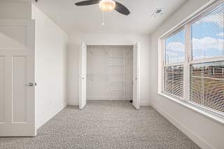 a bedroom with a large window and a ceiling fan  at Signature Pointe Apartment Homes, Alabama