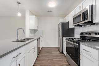 a modern kitchen with stainless steel appliances and white cabinets  at Signature Pointe Apartment Homes, Athens, AL