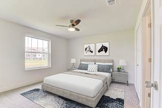 A bedroom with a bed, nightstands, a window and a ceiling fan at Signature Pointe Apartment Homes, Athens