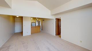 A large living room with a cathedral ceiling and a kitchen with breakfast bar at South Bridge Apartments, Fort Wayne, Indiana